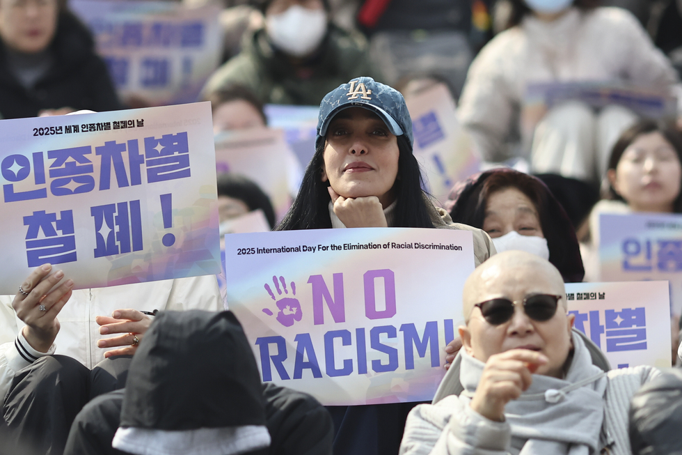 Demonstrators hold a sign reading "No Racism" during a demonstration against racism.
